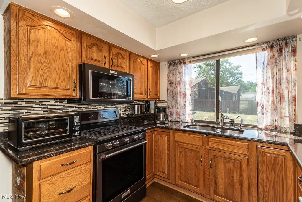 Kitchen with gas stove, granite counters, recessed lighting and view of rear yard