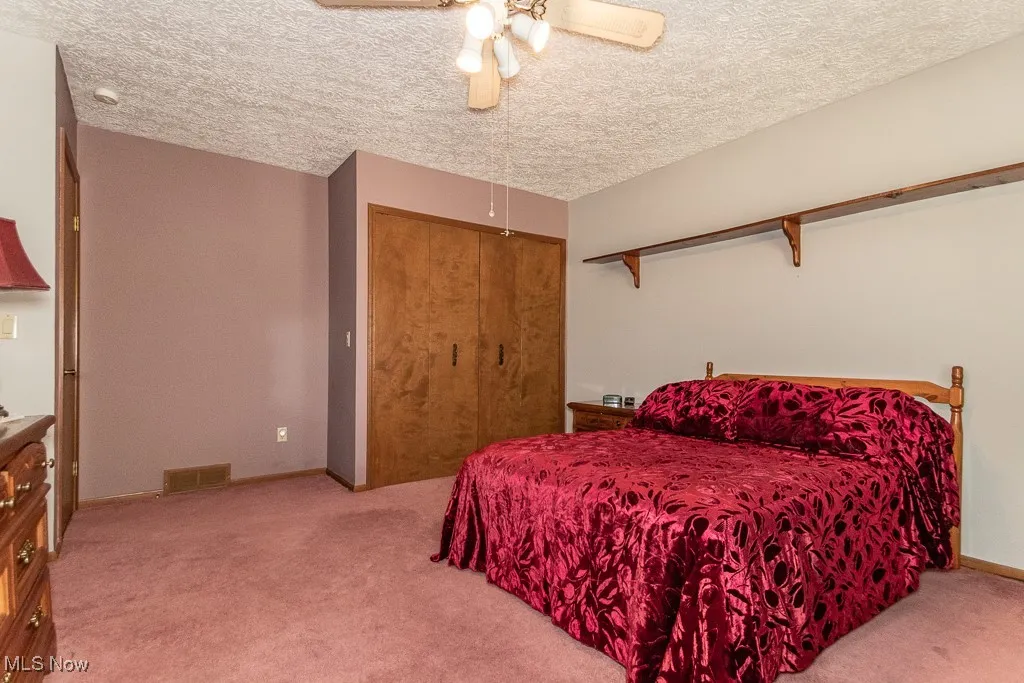Bedroom with light colored carpet, ceiling fan, and a closet