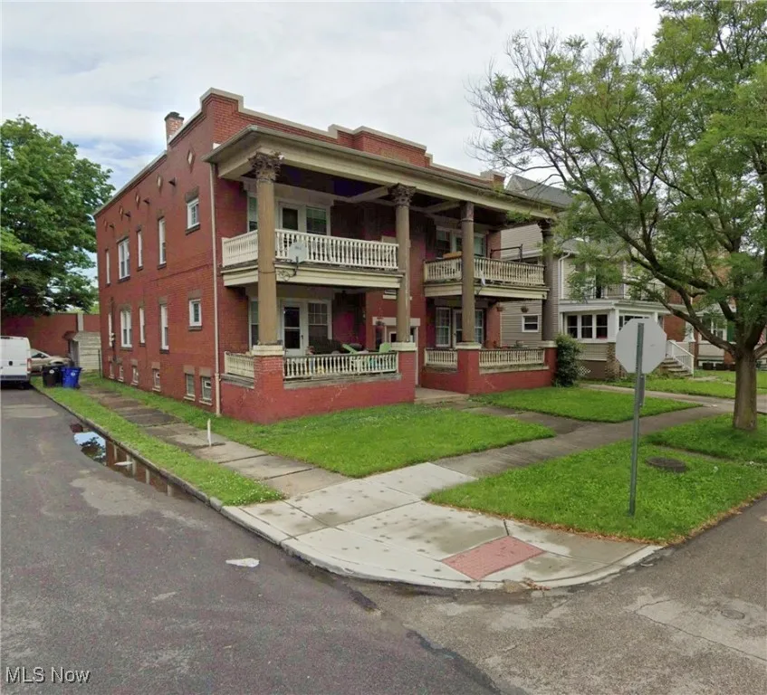 Neoclassical home featuring covered porch, brick siding, a front lawn, and a chimney