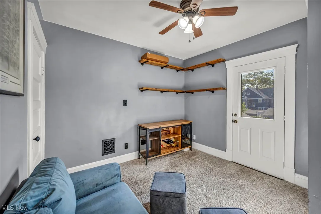 Carpeted living area featuring baseboards and ceiling fan
