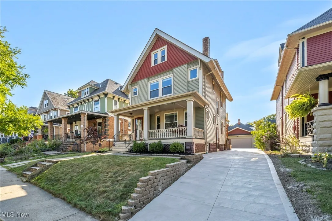 View of front of house with a porch, a chimney, a front lawn, an outdoor structure, and a detached garage