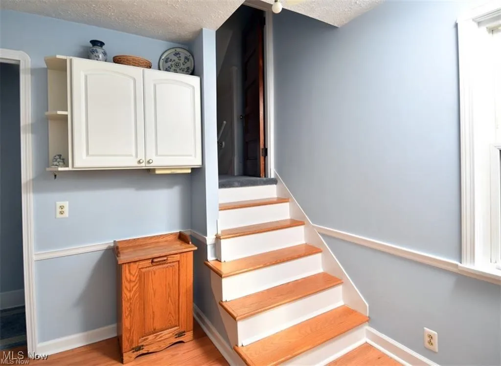 Staircase featuring a textured ceiling and wood finished floors