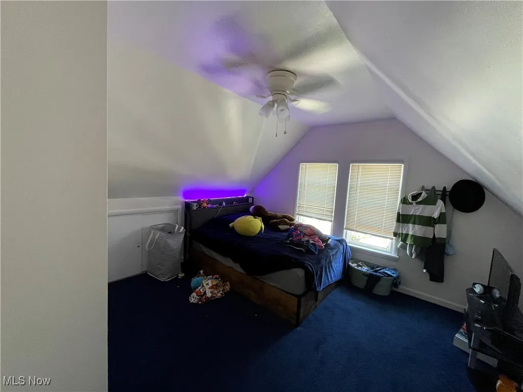 Bedroom featuring dark colored carpet, lofted ceiling, and ceiling fan