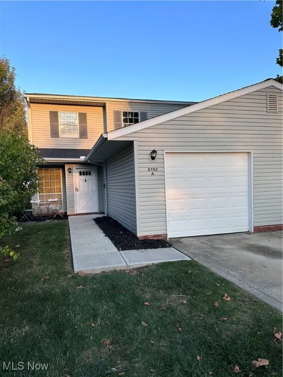 Traditional-style house with driveway, a front lawn, and an attached garage