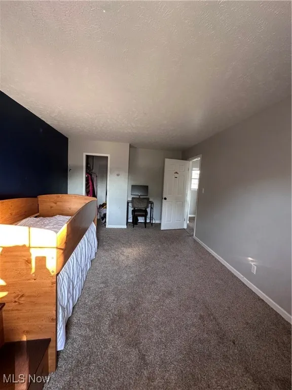 Carpeted bedroom featuring a textured ceiling and baseboards