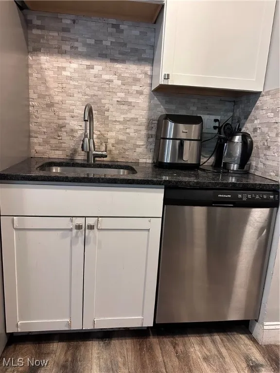 Bar area with dishwasher, white cabinets, backsplash, dark stone counters, and dark wood finished floors