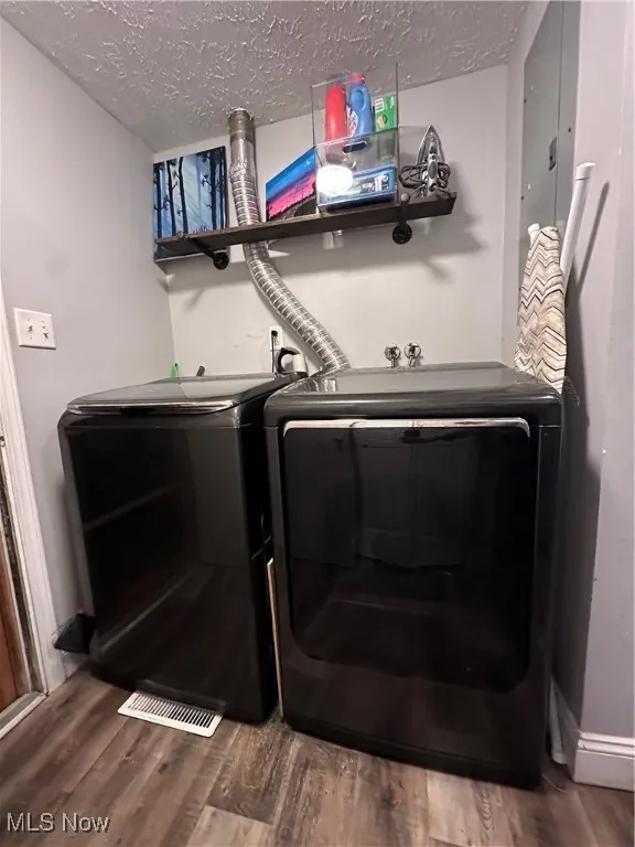 Laundry area featuring dark wood-type flooring, a textured ceiling, and independent washer and dryer