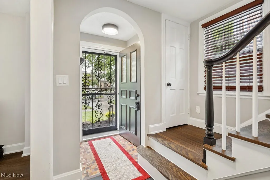 Foyer with arched walkways, dark wood-style flooring, and stairs