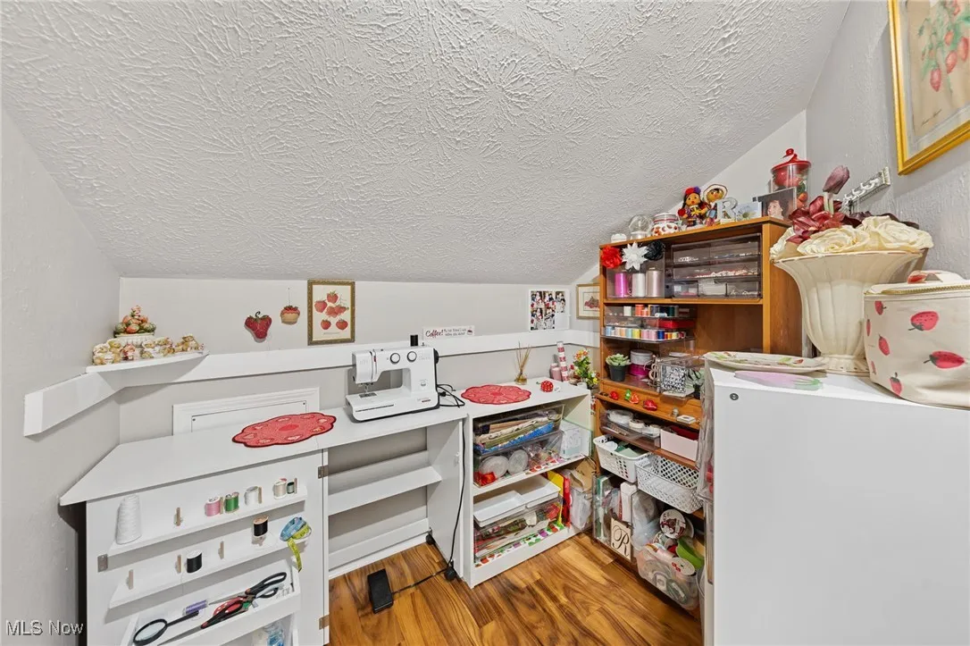 Recreation room featuring lofted ceiling, light wood-style flooring, a textured ceiling, and washer / clothes dryer
