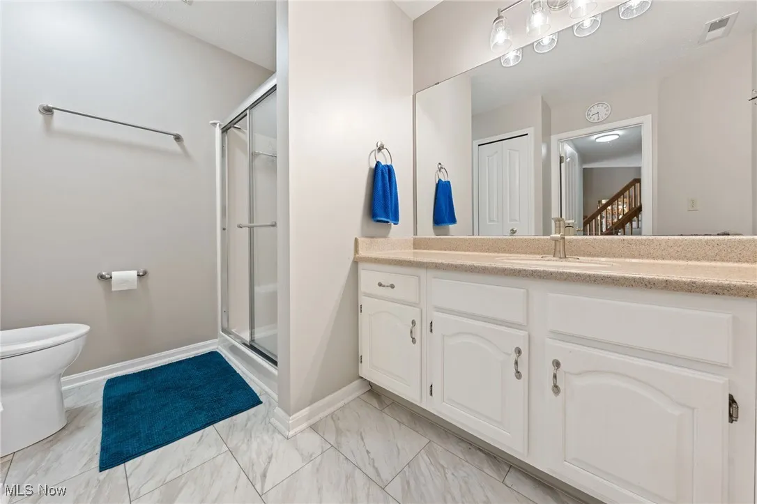 Full bath featuring vanity, a shower stall, and light marble finish floors