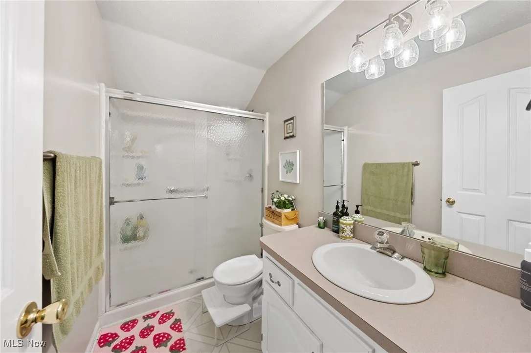 Bathroom with vanity, a shower stall, light tile patterned floors, and lofted ceiling