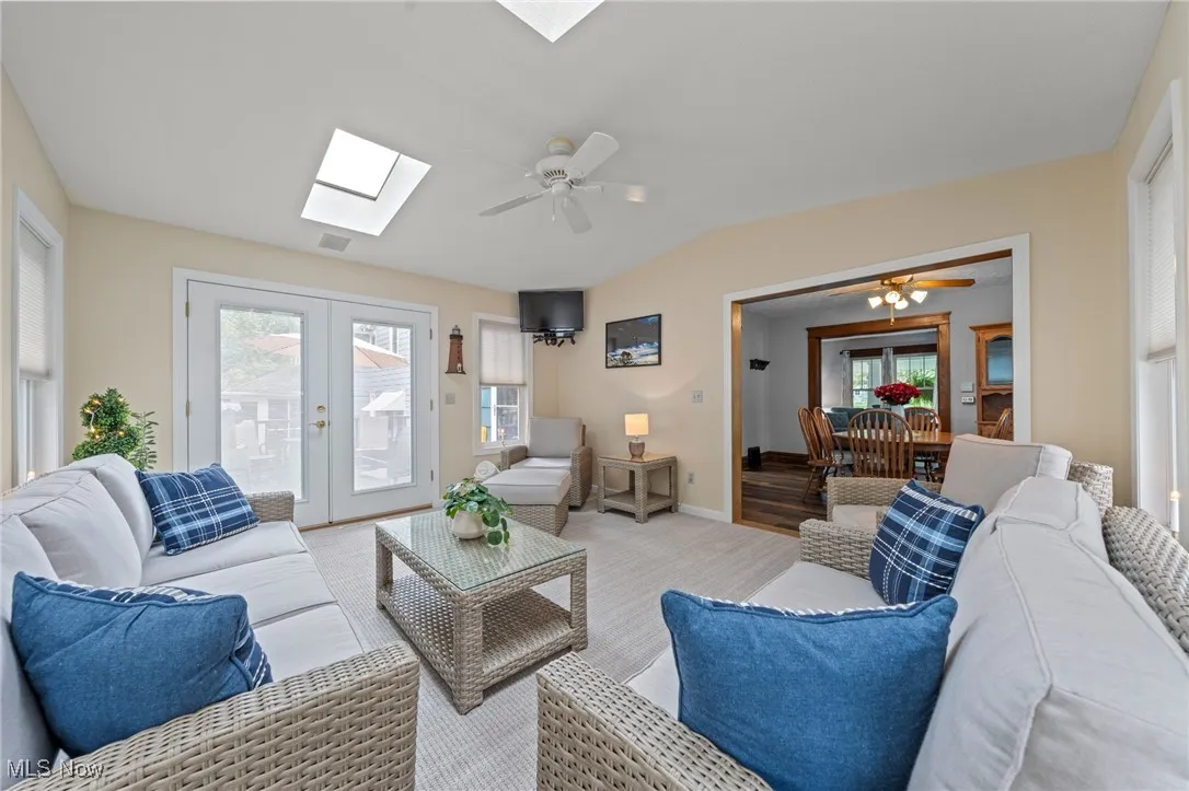 Carpeted Sunroom/4 season room with a skylight, french doors, plenty of natural light, vaulted ceiling, and a ceiling fan