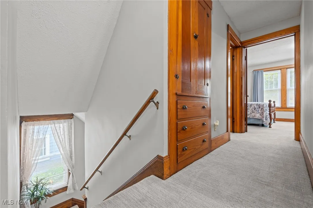 Hallway with an upstairs landing and light colored carpet