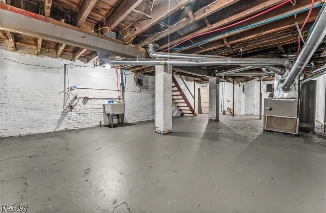 Unfinished basement featuring stairway and heating unit
