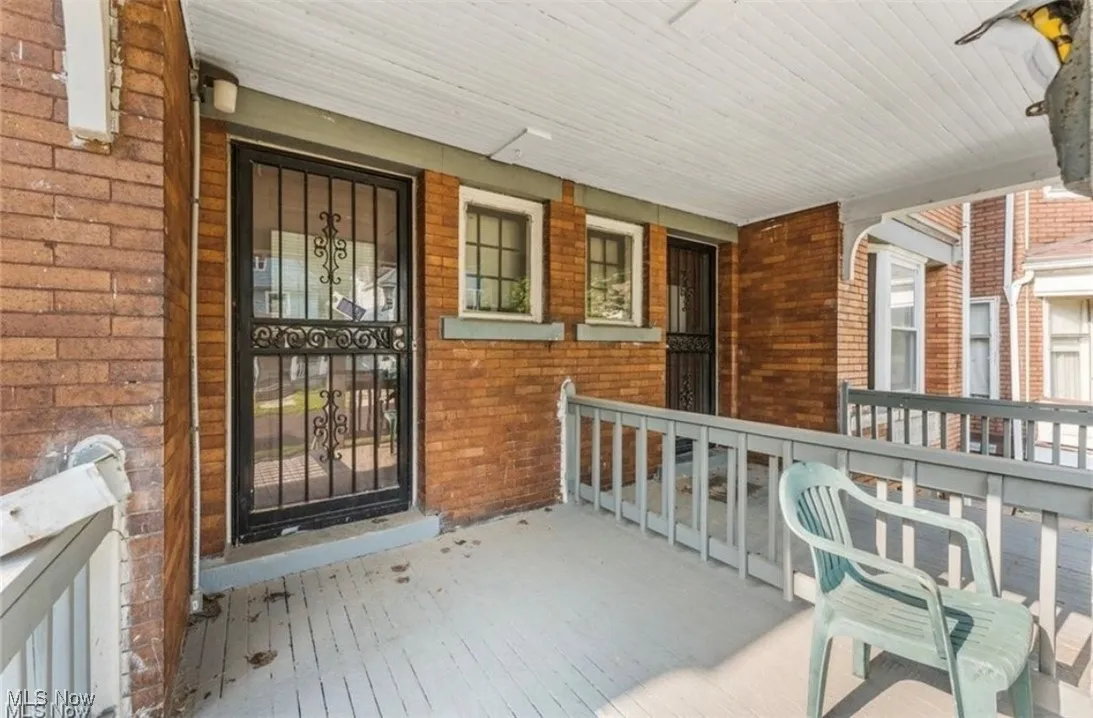 Doorway to property featuring brick siding and a porch