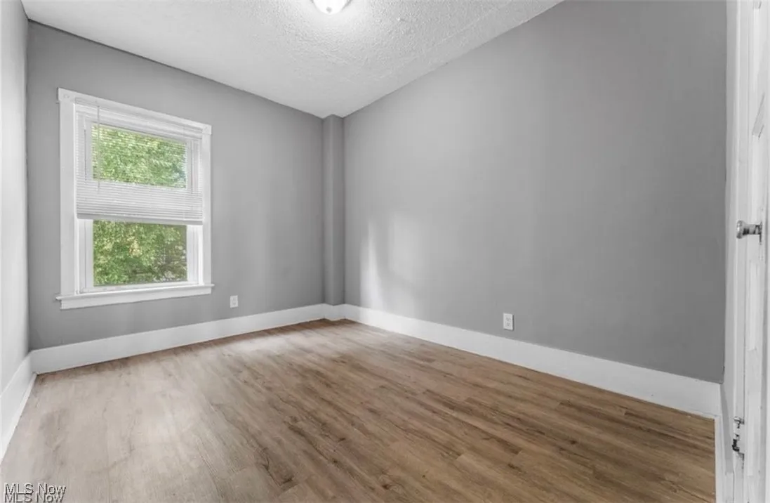 Empty room with light wood-style flooring and a textured ceiling