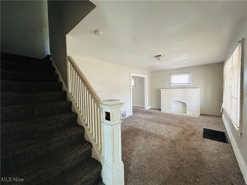 Stairs featuring carpet flooring and a brick fireplace