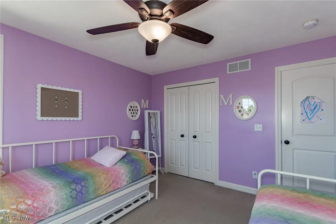 Bedroom with carpet floors, ceiling fan, and a closet