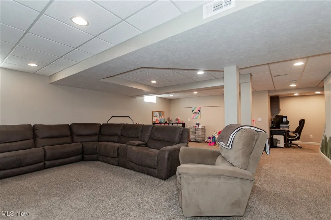 Living area with a drop ceiling, light colored carpet, an office area, and recessed lighting