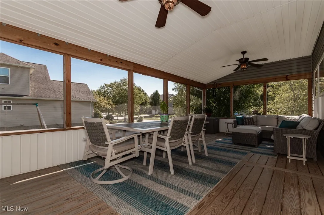 Sunroom / solarium featuring a wooden deck, outdoor dining area, ceiling fan, an outdoor hangout area, and lofted ceiling