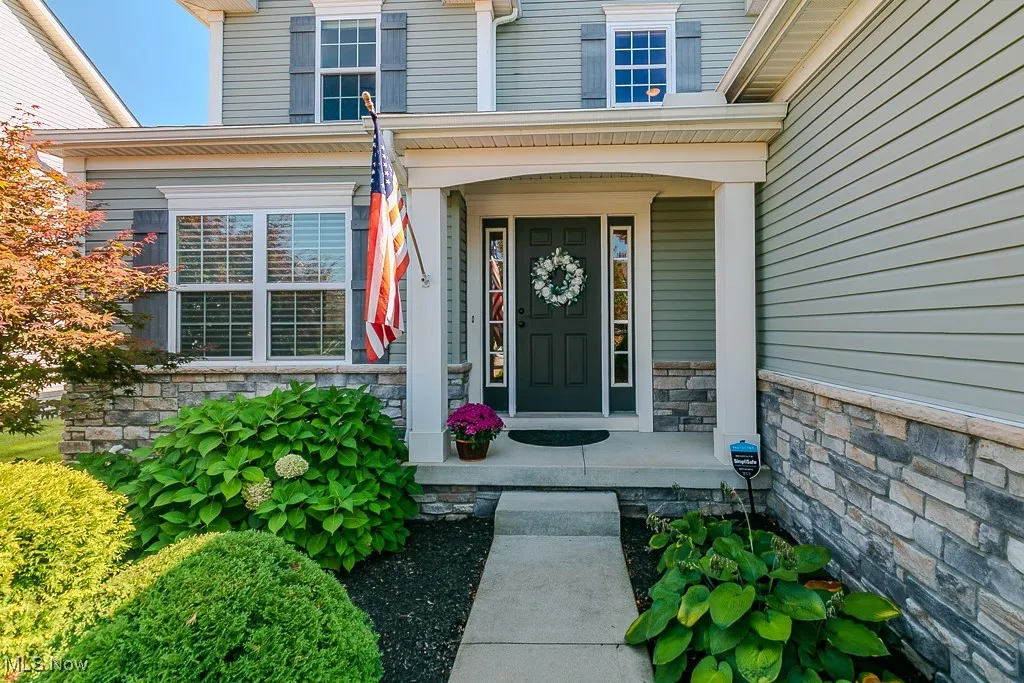 Doorway to property with stone siding and a porch