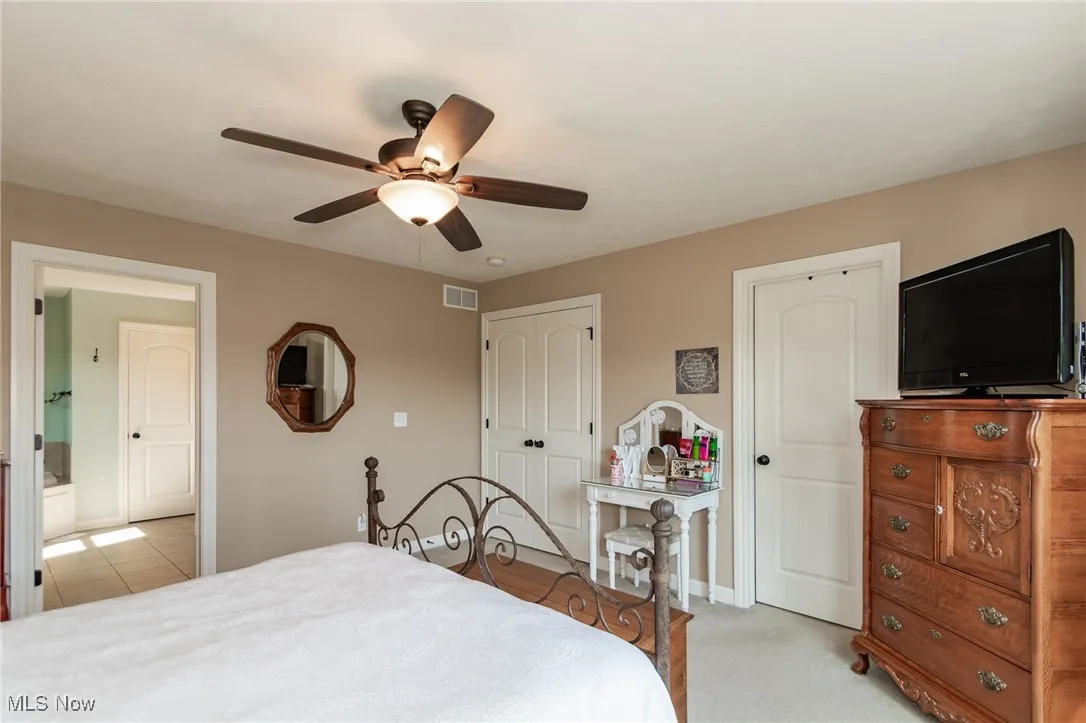 Bedroom with a closet, a ceiling fan, and light carpet