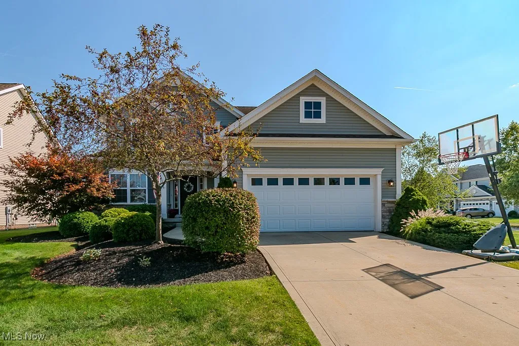 View of front of home with stone siding, a front yard, driveway, and a garage