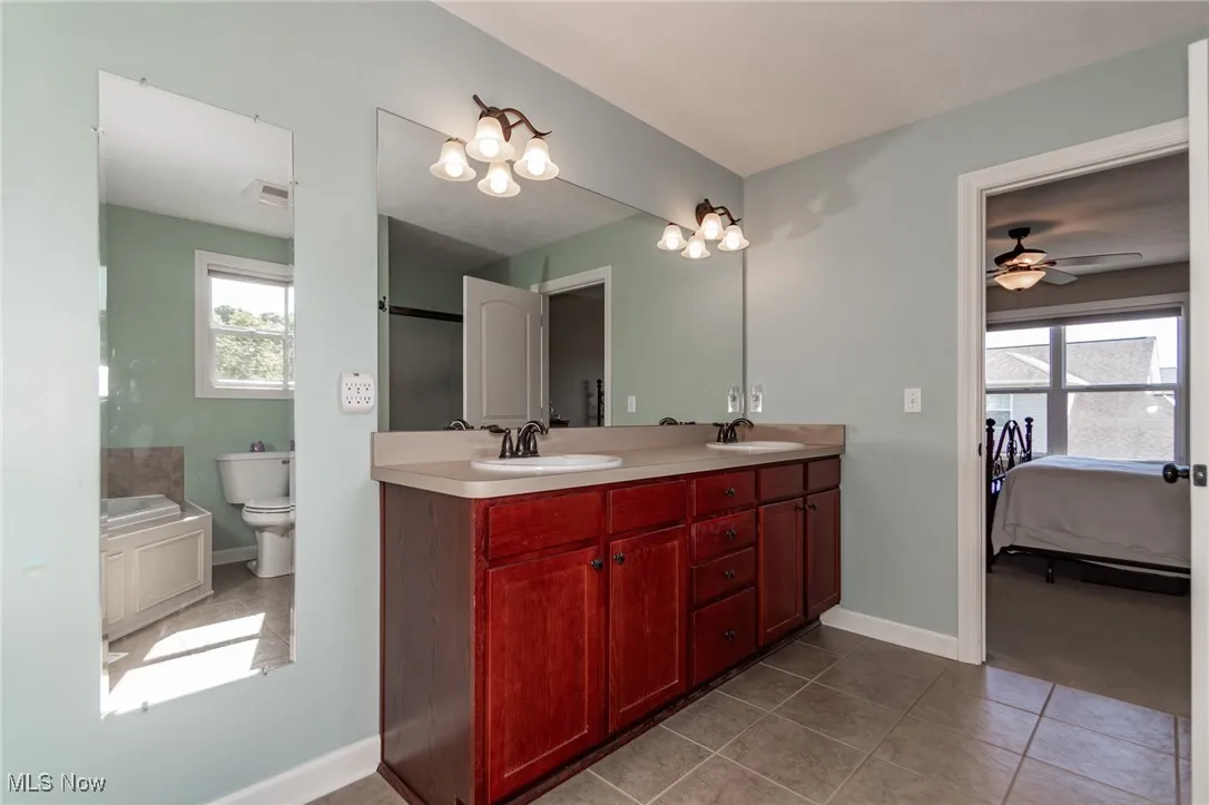 Bathroom with connected bathroom, double vanity, plenty of natural light, and dark tile patterned flooring