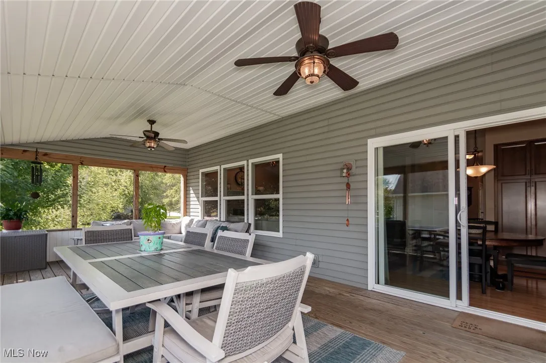 Sunroom / solarium with outdoor dining space, a wooden deck, outdoor lounge area, and a ceiling fan