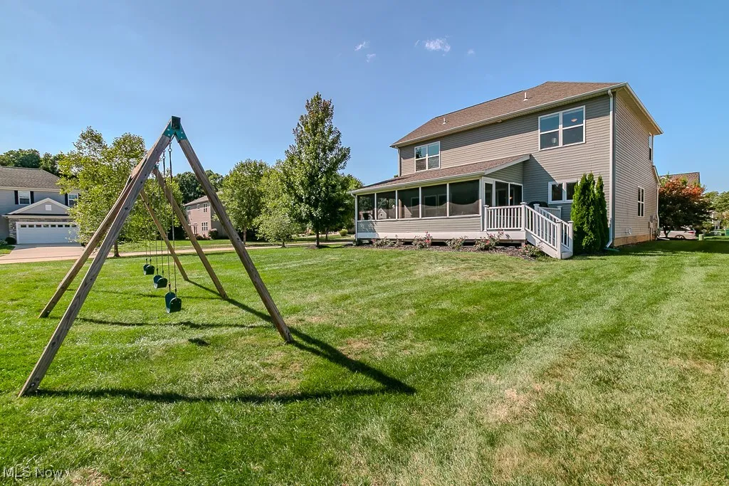 Back of house with a lawn, a sunroom, and a playground