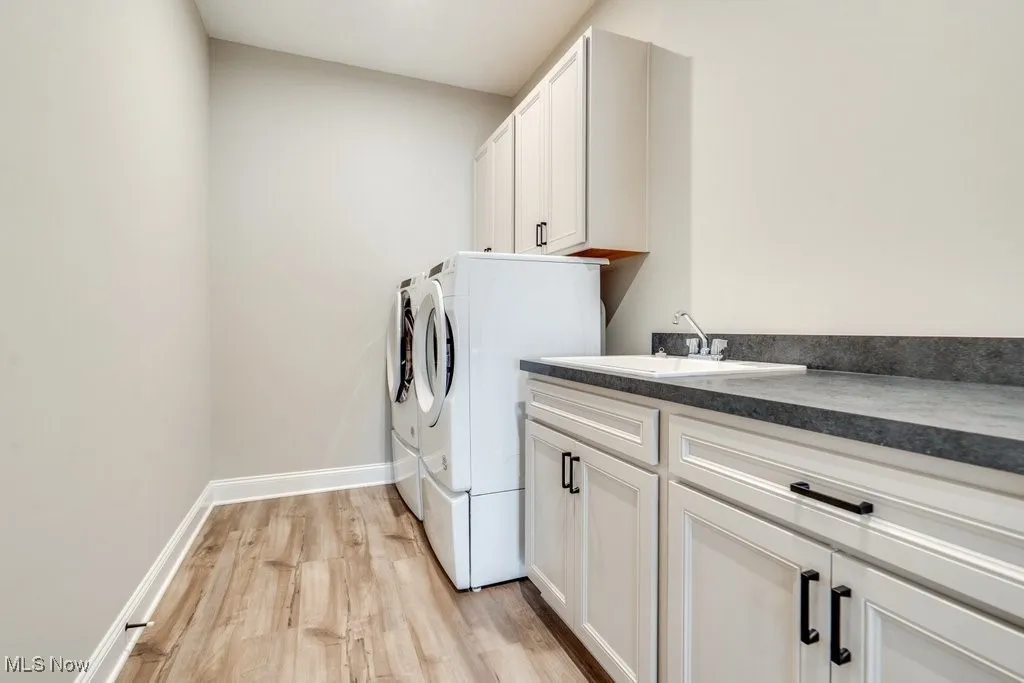 Laundry room featuring light wood-style floors, cabinet space, and separate washer and dryer