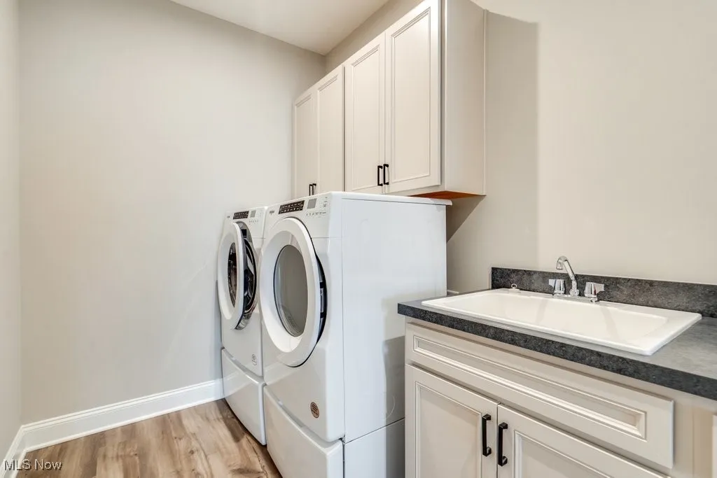Laundry room featuring light wood finished floors, independent washer and dryer, and cabinet space