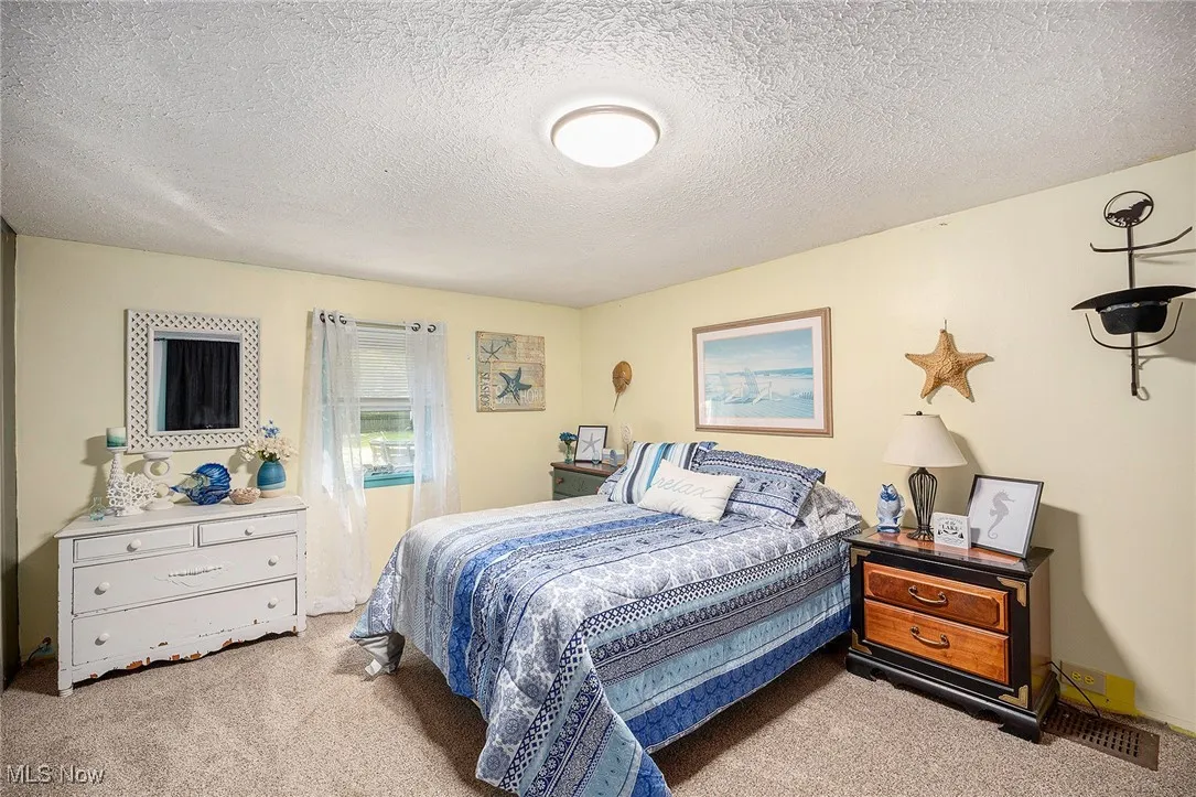 Bedroom with light colored carpet and a textured ceiling