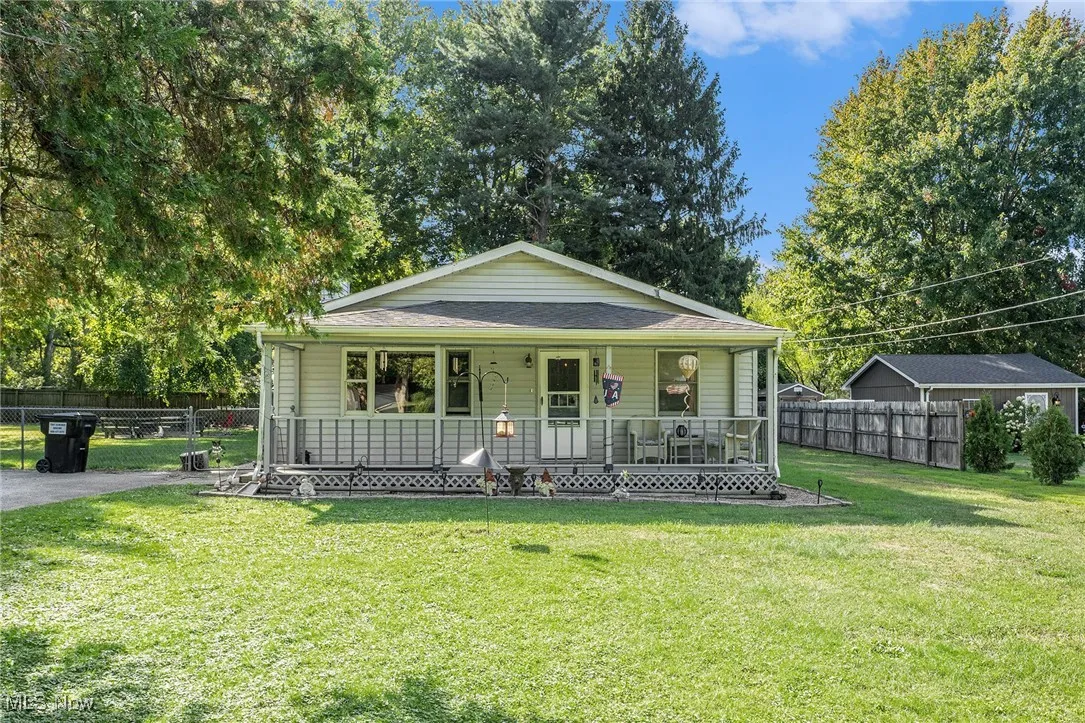 View of front of house with covered porch, view of scattered trees, and a shingled roof