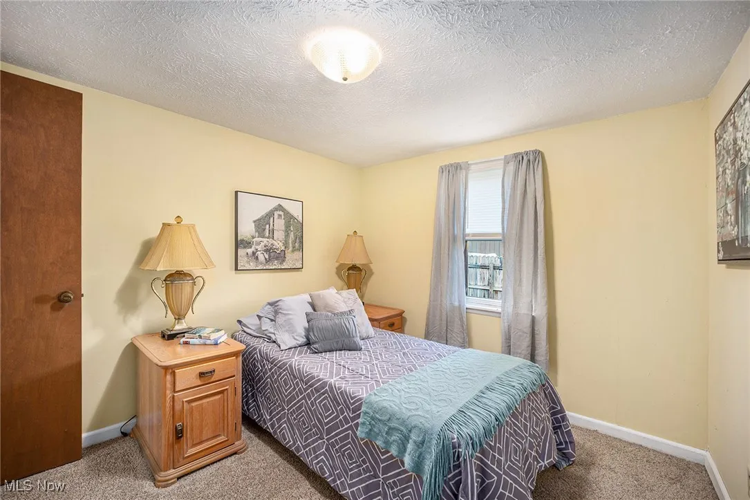 Carpeted bedroom with baseboards and a textured ceiling