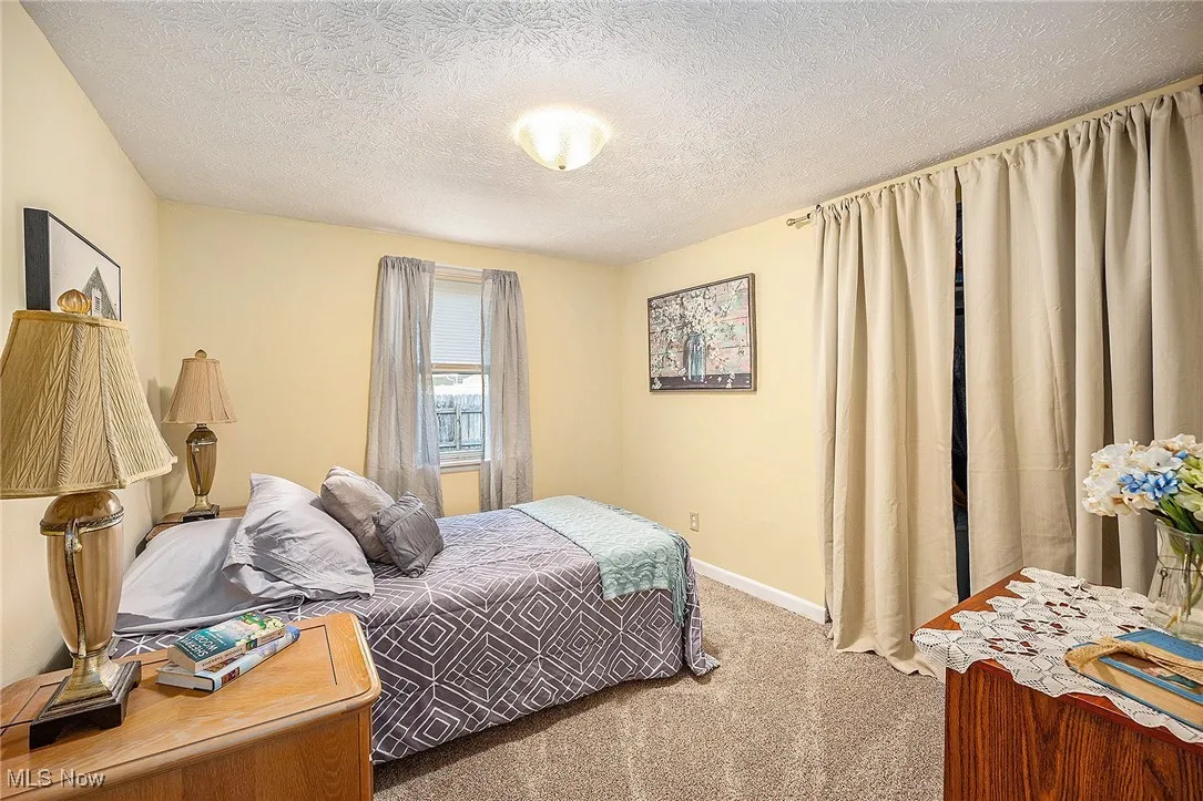 Carpeted bedroom with a textured ceiling and baseboards