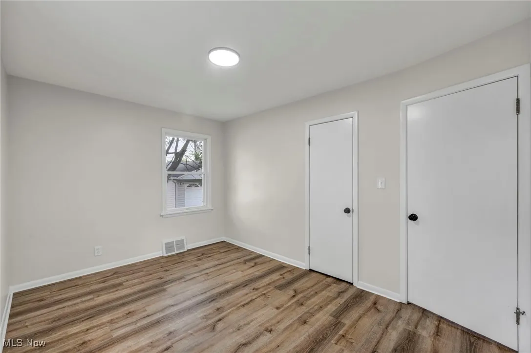 Unfurnished bedroom with wood finished floors and baseboards