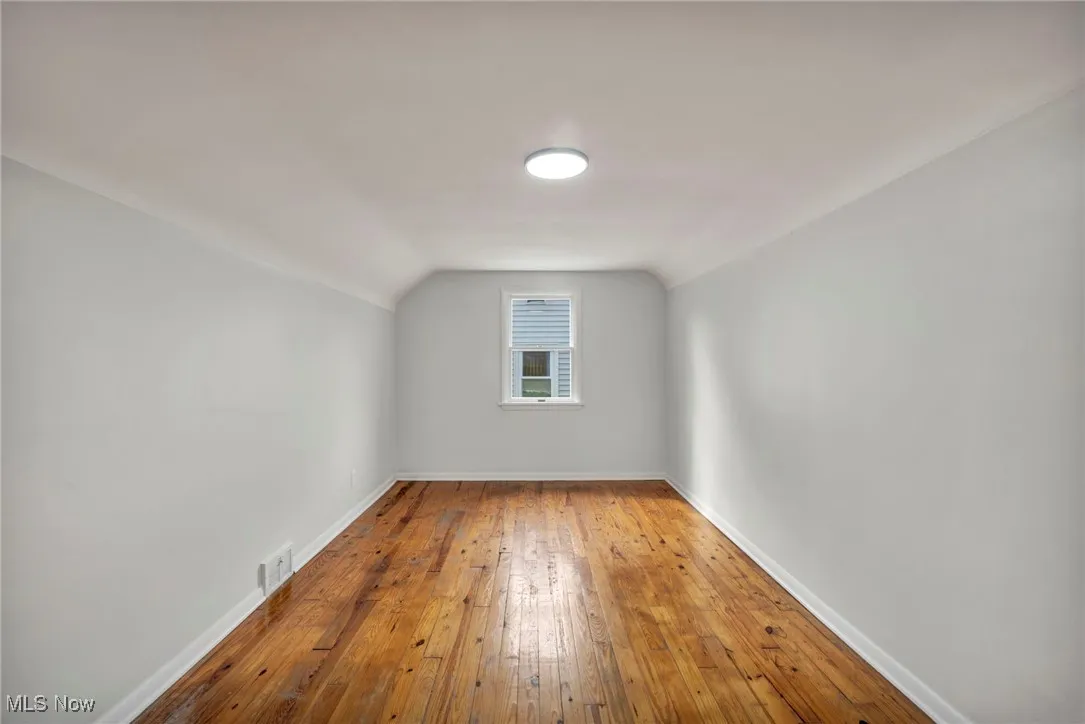Additional living space featuring wood-type flooring and vaulted ceiling