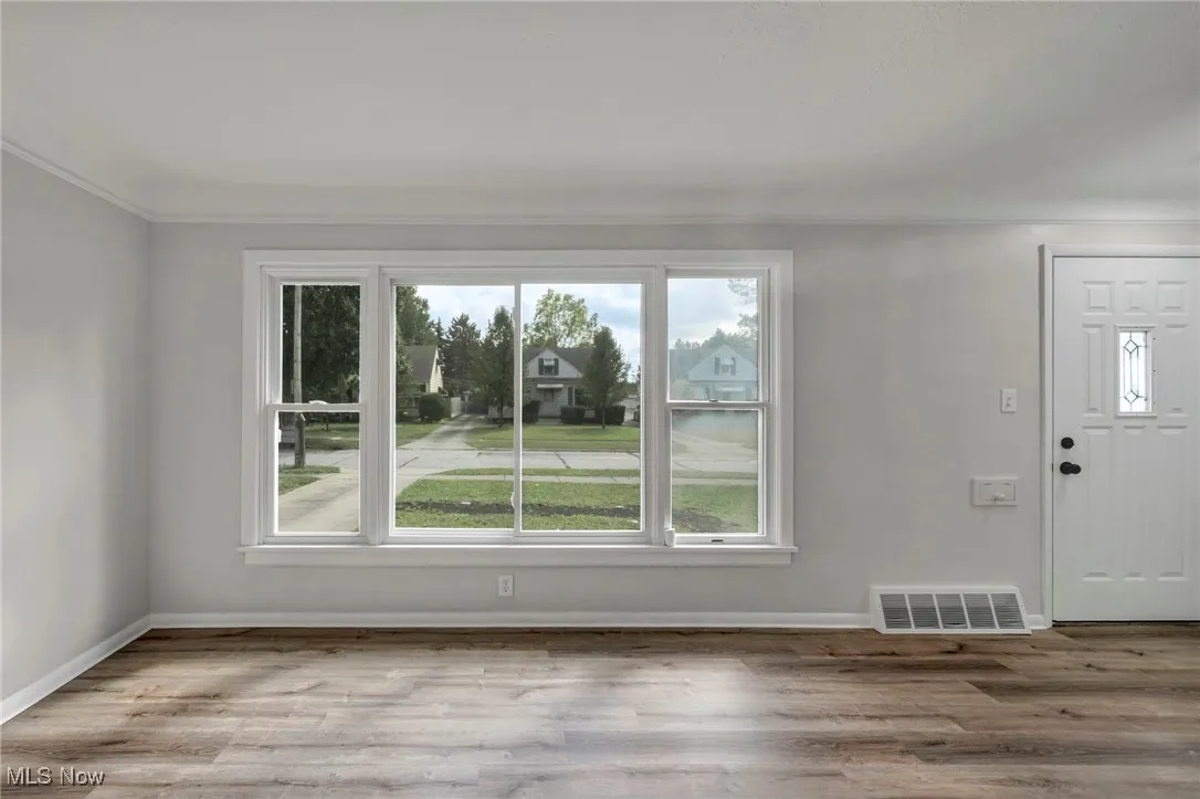 Unfurnished living room featuring plenty of natural light, wood finished floors, and ornamental molding