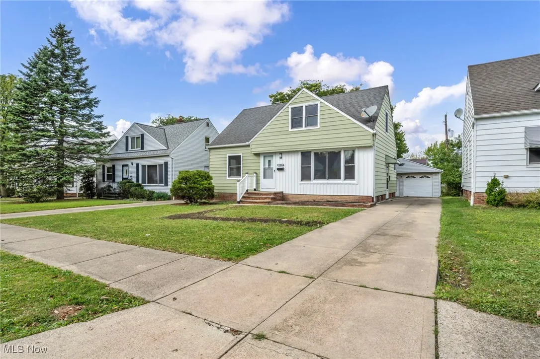 View of front of property with a front yard, an outbuilding, a shingled roof, and board and batten siding