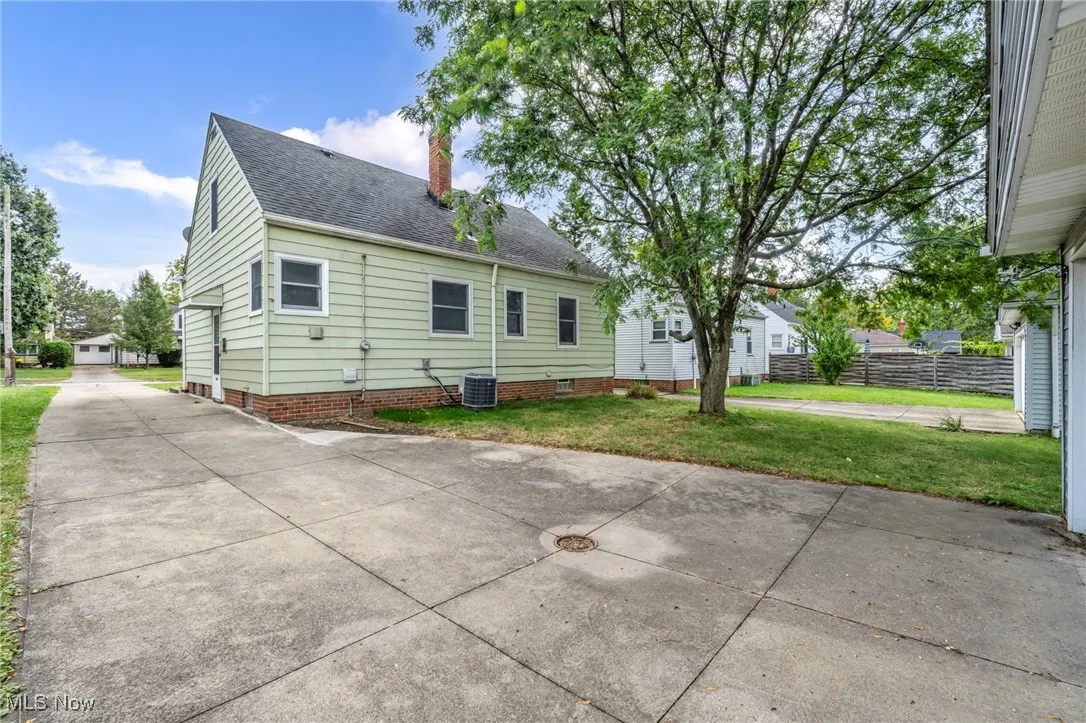 Back of house featuring a chimney, a shingled roof, driveway, crawl space, and a patio area