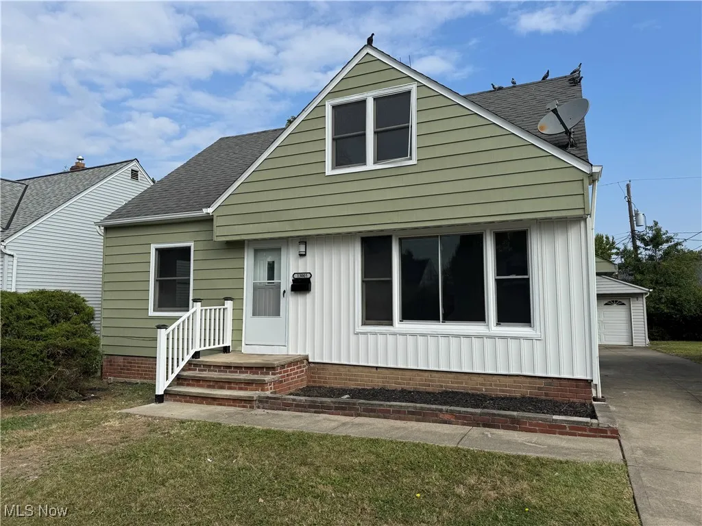 Bungalow with a shingled roof, a front yard, a garage, and board and batten siding