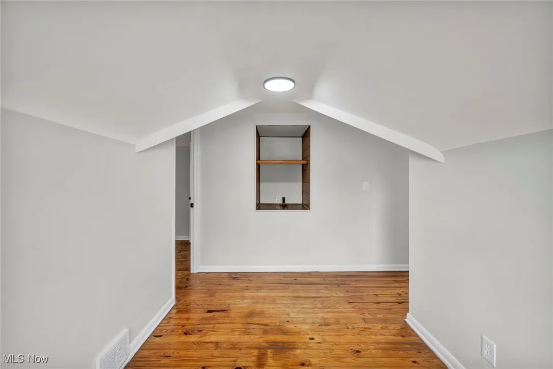 Bonus room with light wood finished floors and vaulted ceiling