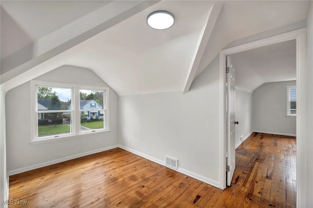 Additional living space with hardwood / wood-style flooring, healthy amount of natural light, and vaulted ceiling