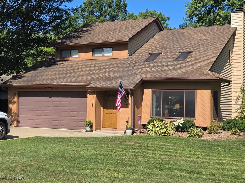 View of front facade featuring a shingled roof, driveway, and a front yard