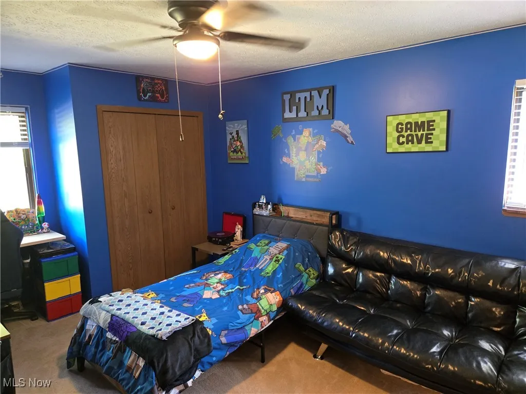 Bedroom featuring multiple windows, carpet floors, a textured ceiling, and a closet