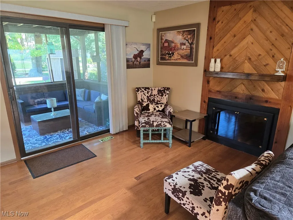 Sitting room featuring a glass covered fireplace and wood finished floors