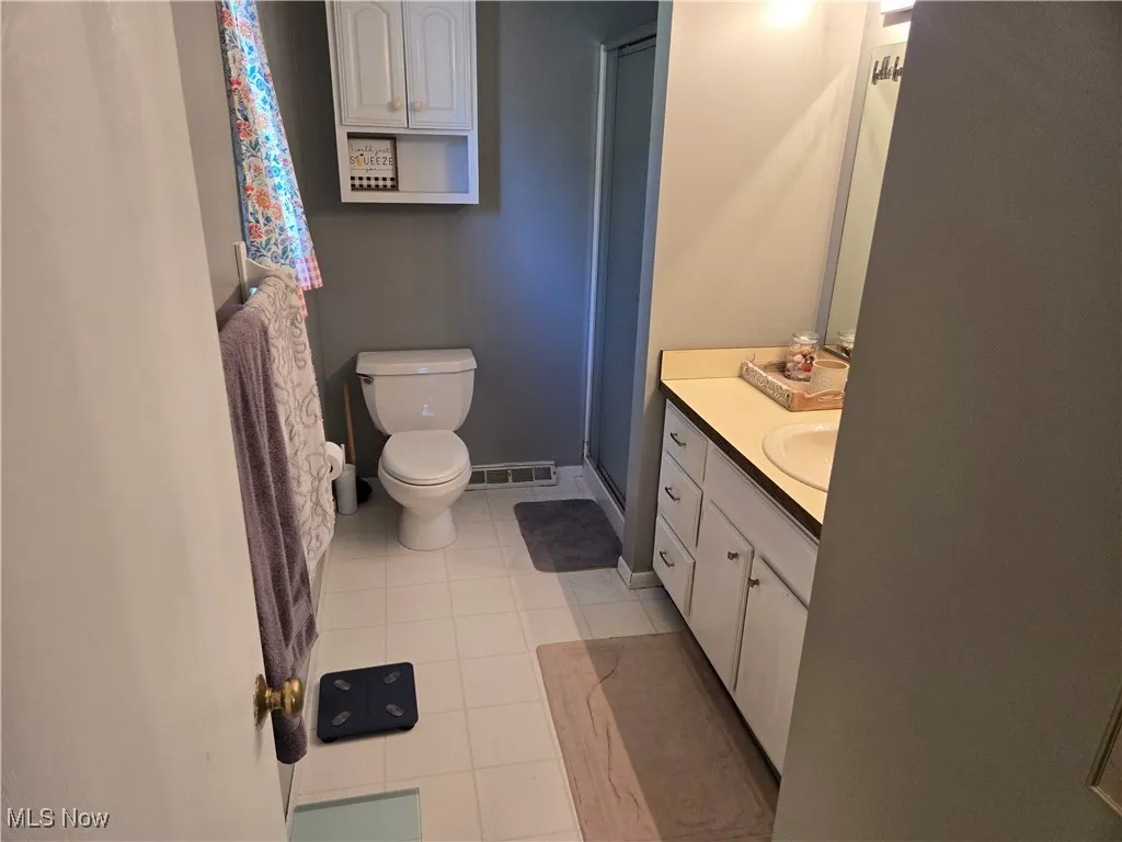 Bathroom featuring vanity, light tile patterned floors, and a shower stall