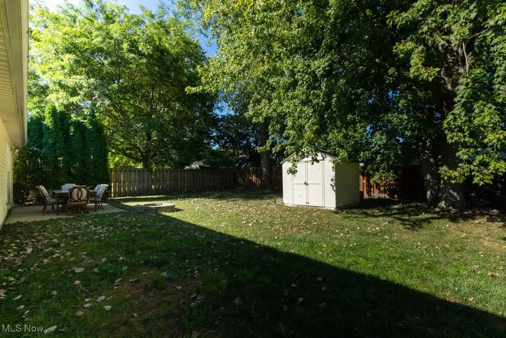 Fenced backyard featuring a storage shed and a patio