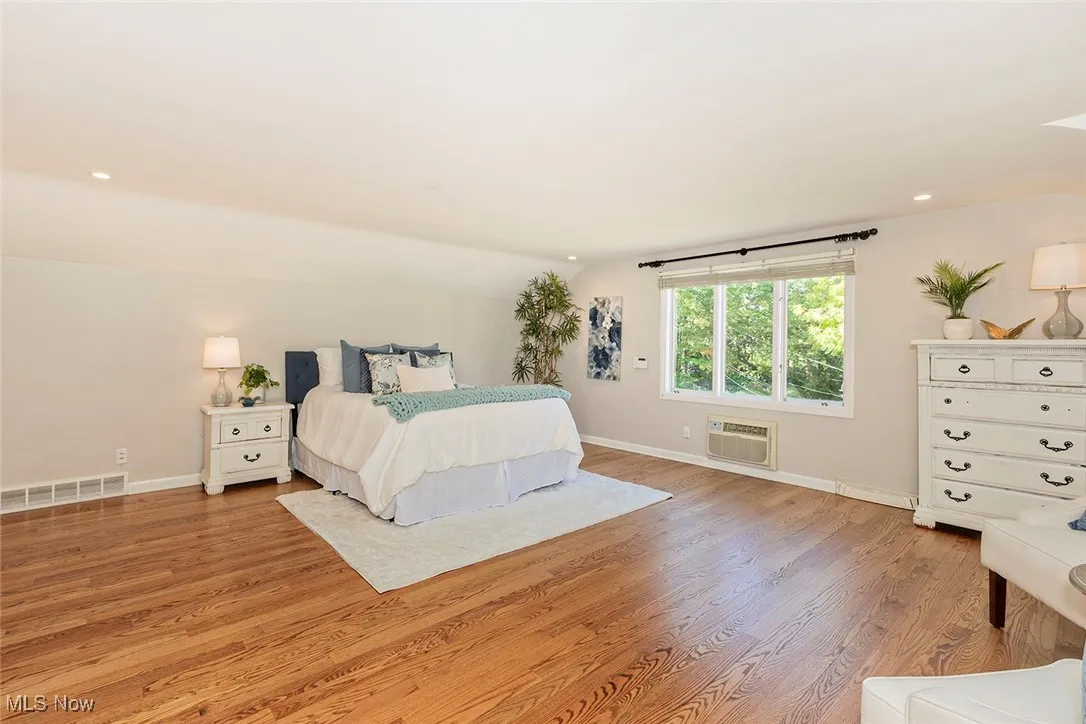 Primary bedroom with recessed lighting, wood finished floors, and vaulted ceiling